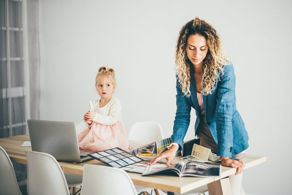 Business mom with daughter working with laptop at home.