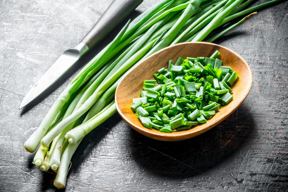 Chopped green onion in a wooden plate.