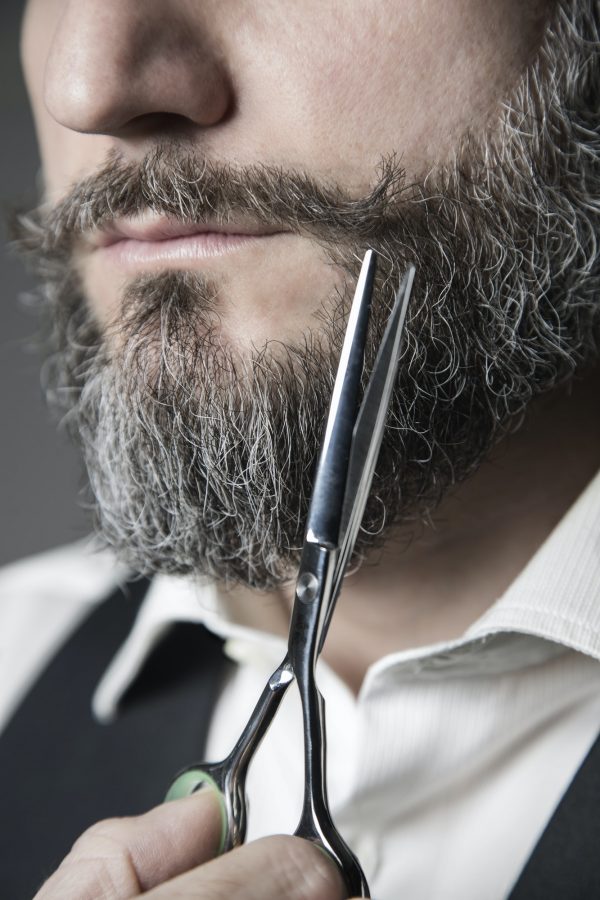 man adjusting his mustache with scissors