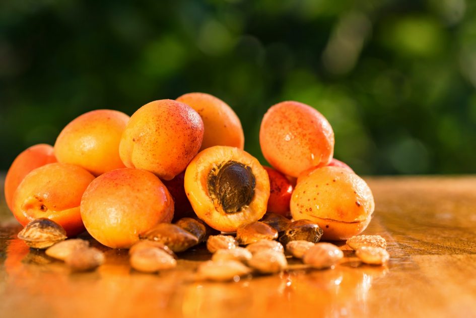 Fresh apricots and seeds on wooden surface
