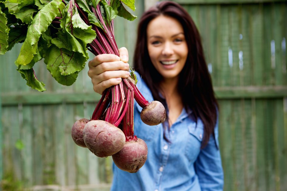 Smiling woman showing a bunch of beetroots