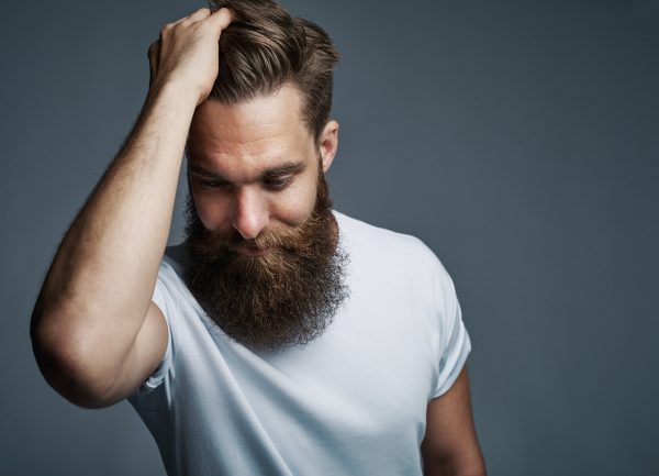 Thinking bearded man holding hair and laughing
