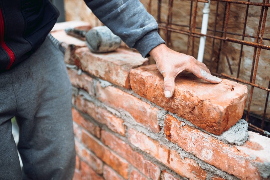 construction worker laying bricks and building walls on construction site
