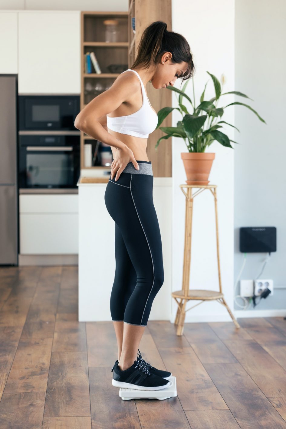 Healthy young woman looking if she has lost weight on scale weight at home.