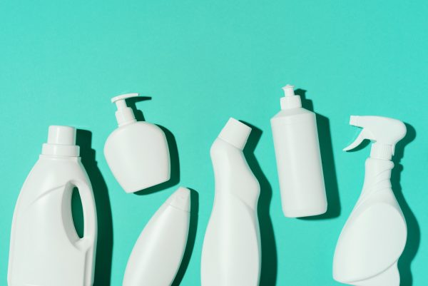 Pattern of white plastic bottles, containers of chemical cleaning products on blue background. Top