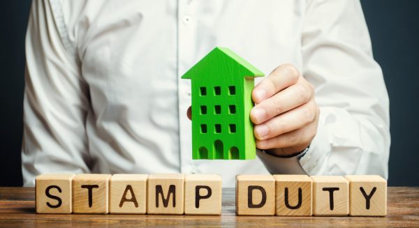 Businessman and wooden blocks with the word Stamp duty and house