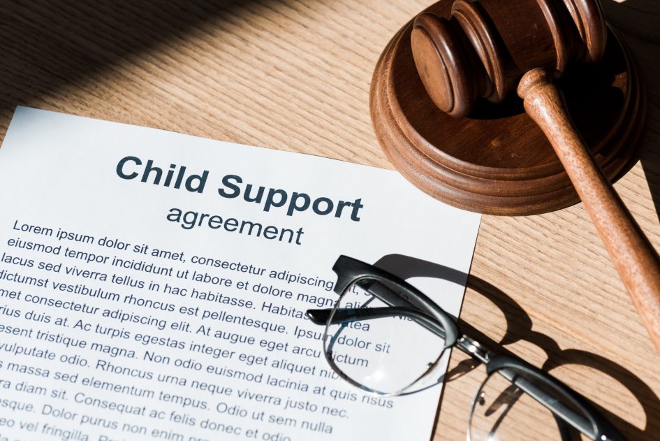 wooden gavel near document with child support agreement and glasses
